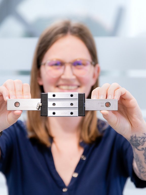 Patrick Fasching, Produktmanager für Lineartechnik bei HENNLICH, hält eine Linearführung in beiden Händen.